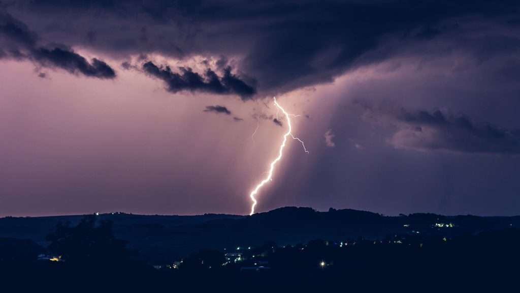 Bolt of lightning during a thunderstorm. withy a purple sky background.
