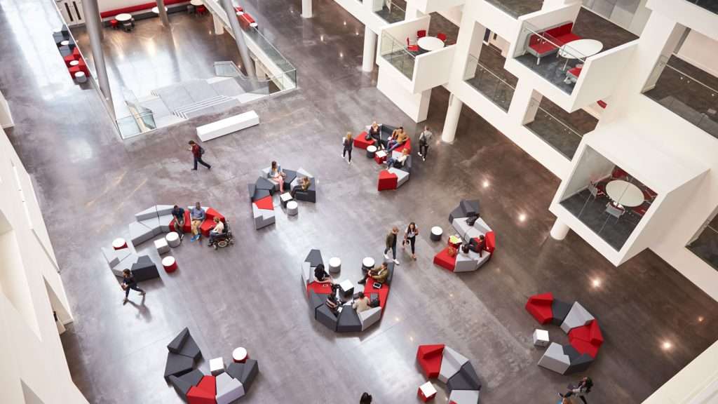 Students sitting in the atrium of a modern uni.