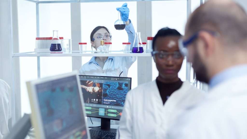 3 people working in a laboratory in white PPE gear