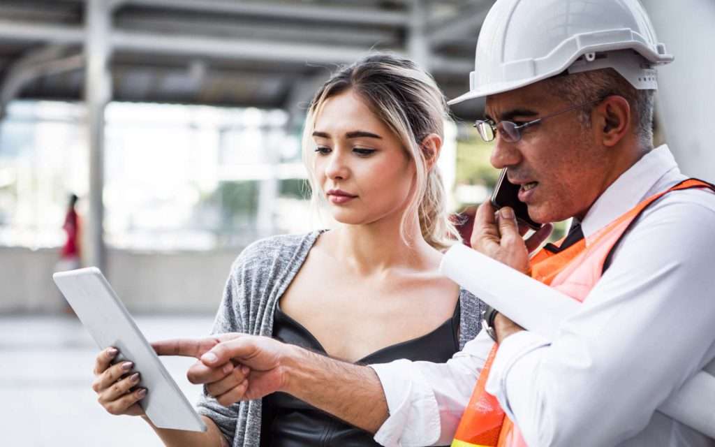 Two site managers on a new site referring to tasks on a tablet.